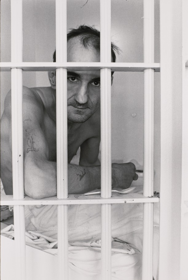 Untitled (Inmate with tatoo on arm, looking through bars)