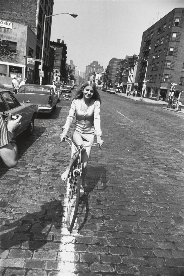 Untitled (Woman riding a bicycle barefoot down a street)